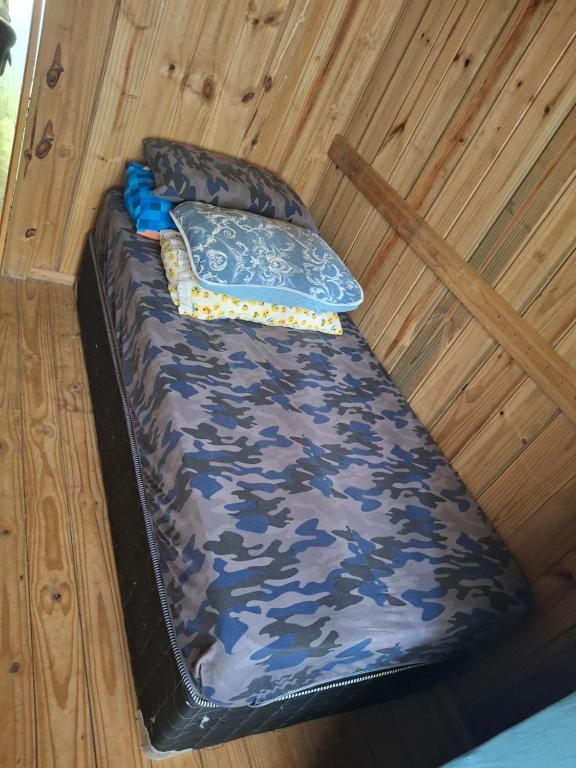 a camo bed in a wooden cabin with a pillow at Siio do bambu in Joinville