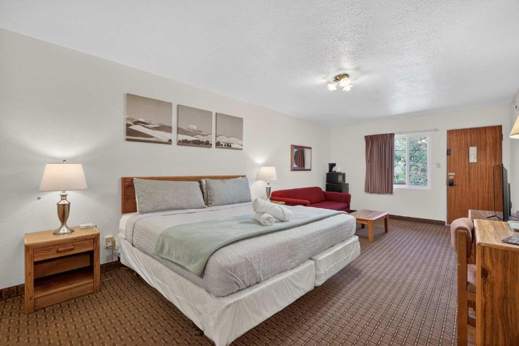 a bedroom with a large bed and a red couch at Eagle Motel Suite 107 in Manitou Springs