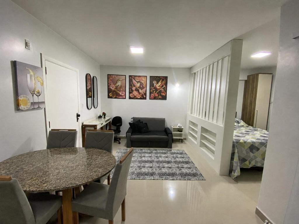 a living room with a dining room table and a bedroom at Flat da Belly 904-A Hidro Piscina Praia in São Vicente