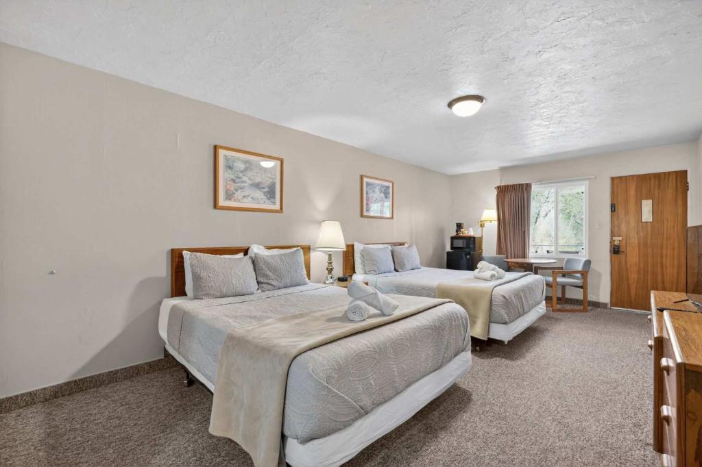 a hotel room with two beds and a desk and a window at Eagle Motel Suite 114 in Manitou Springs
