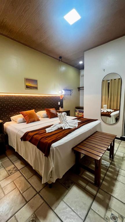 a bedroom with a large bed and a bench at Pousada São José in Barreirinhas