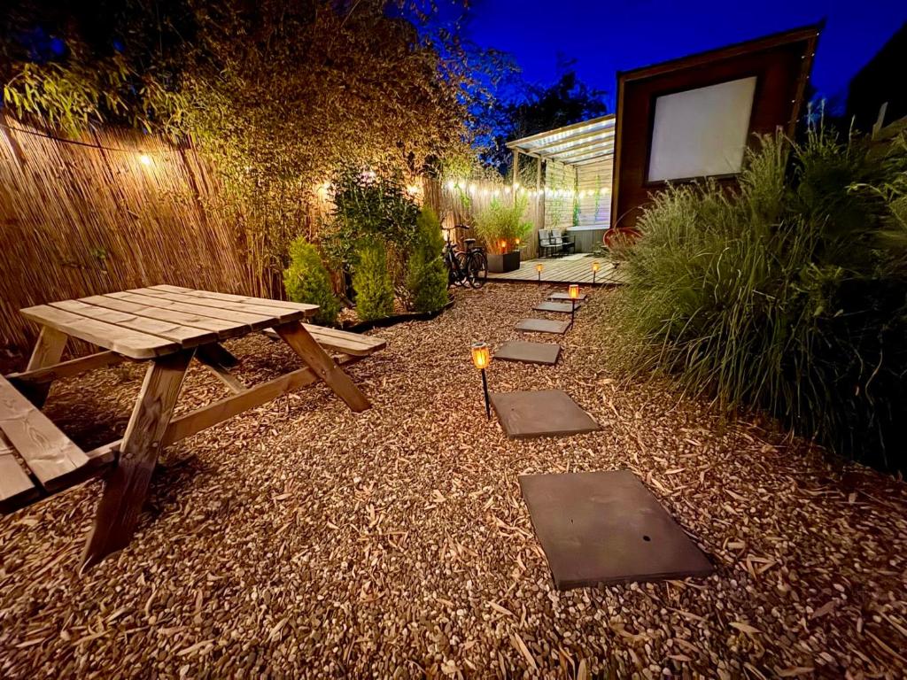 a backyard with a wooden picnic table and a bench at Romantic Tiny House with Private Jacuzzi and Garden between Amsterdam Haarlem and Schiphol Airport in Vijfhuizen