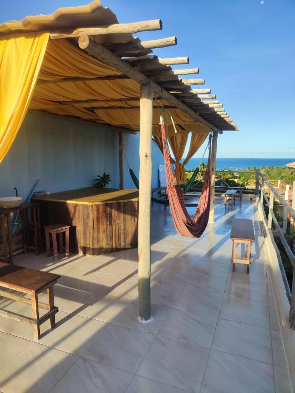 a patio with a hammock and a view of the ocean at Hostel Leda Beach in Canoa Quebrada