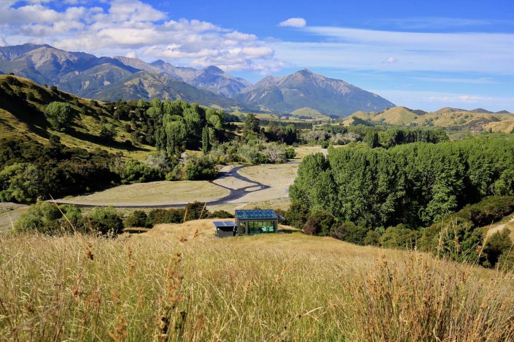 a view of a field with mountains in the background at Kahutara PurePod in Kaikoura