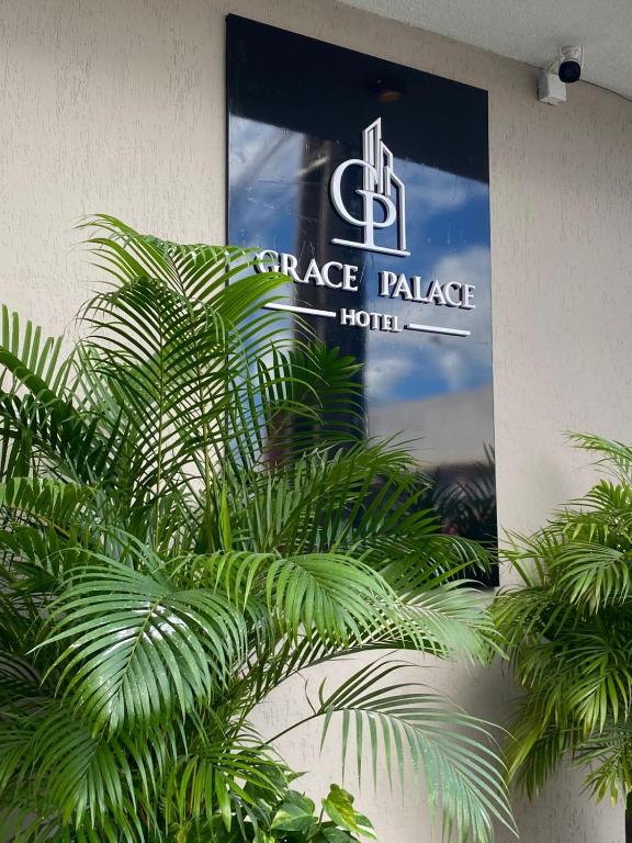 a sign on the side of a building with palm trees at Grace Palace Hotel in Sobral