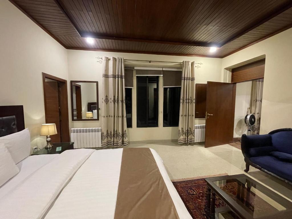 a bedroom with a large bed and a blue chair at Heritage Cottage Kashmir Point in Murree