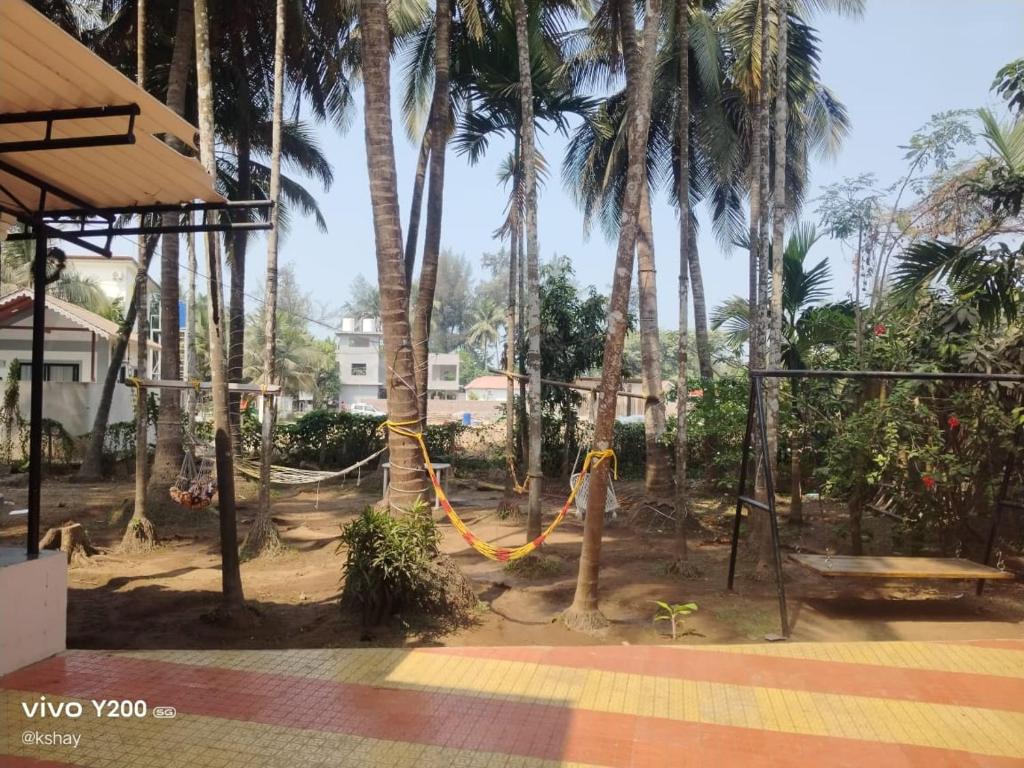 a playground with a hammock and palm trees at Taksh Stay in Nagaon