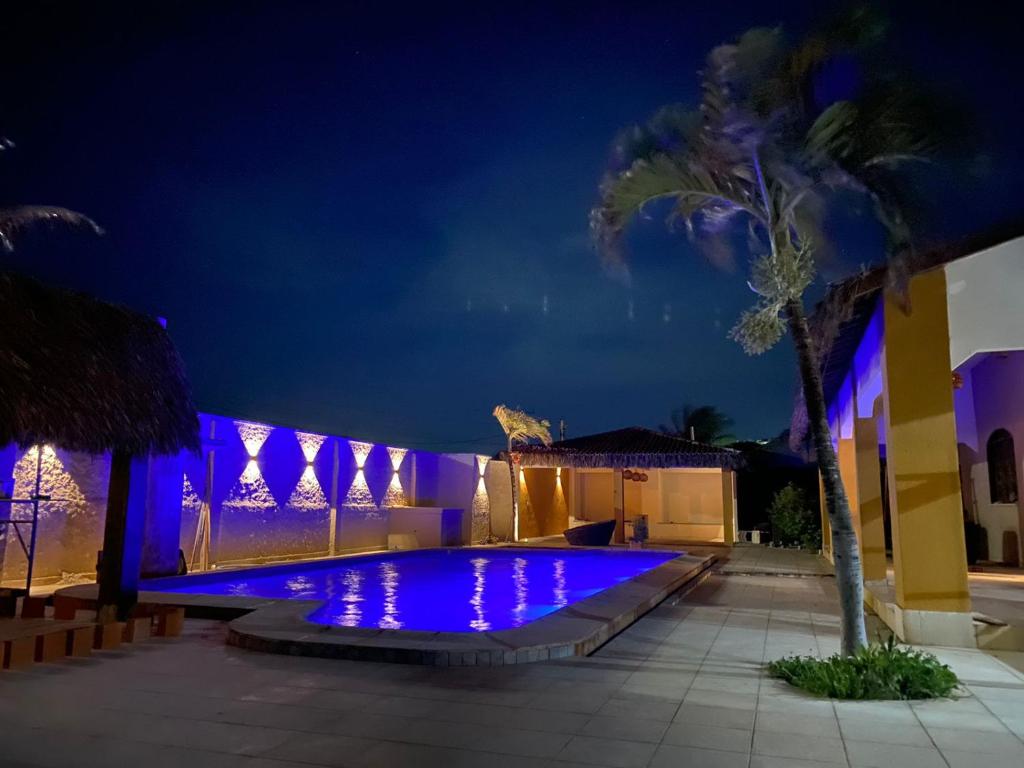 a swimming pool lit up at night with purple lights at Pousada Villa do Sol Taiba in Taíba