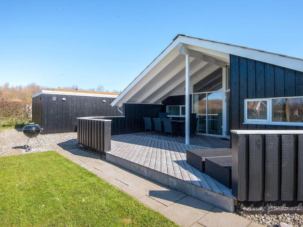 a black house with a deck with a grill at 8 person holiday home in Sydals in Neder Lysabild