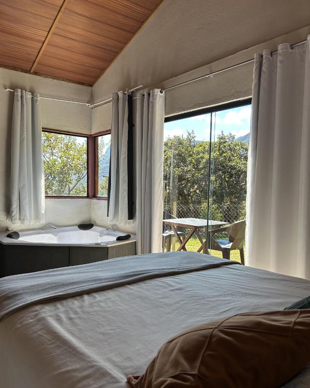 a bedroom with a bed and a tub and a window at Chalé Lumiar in Santana do Riacho