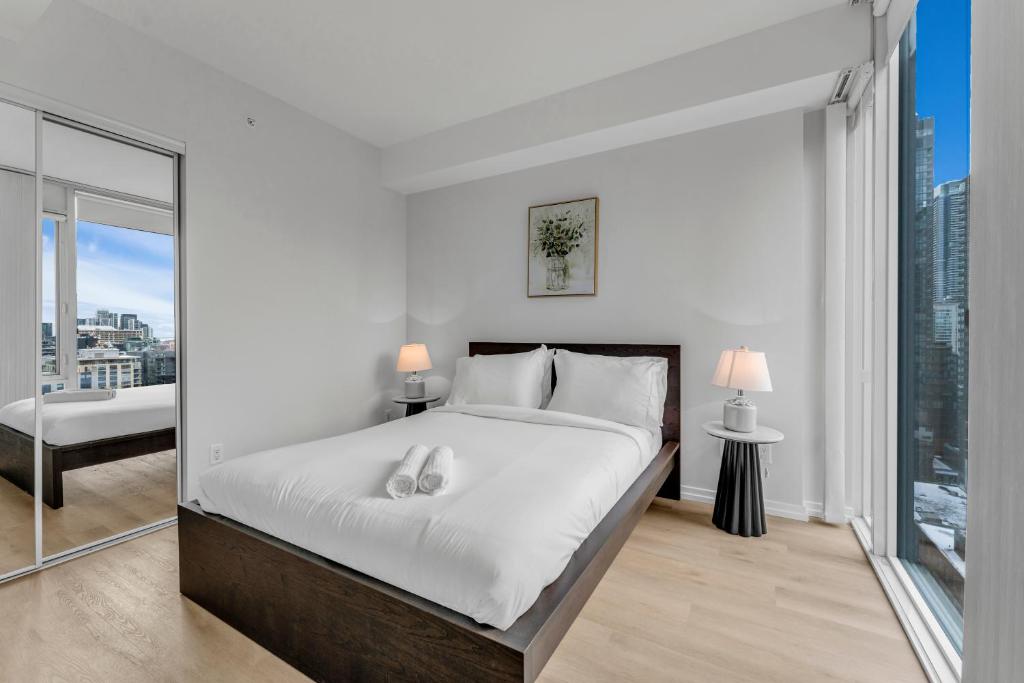 a white bedroom with a large bed and a window at Altitude Residences in Toronto