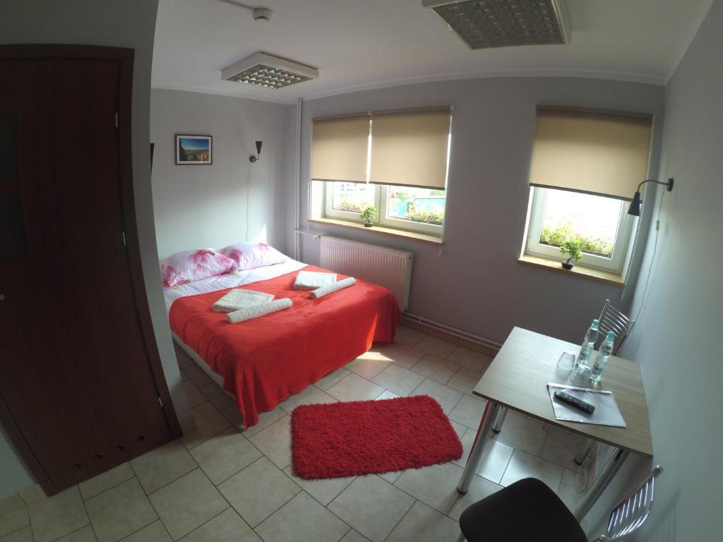 a bedroom with a red bed and two windows at Hostel Bazar in Kraków