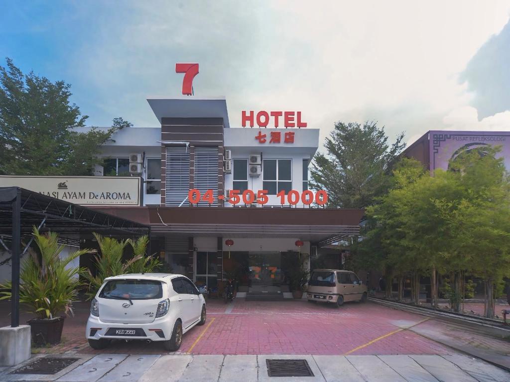 a hotel with two cars parked in a parking lot at 7 Hotel in Juru