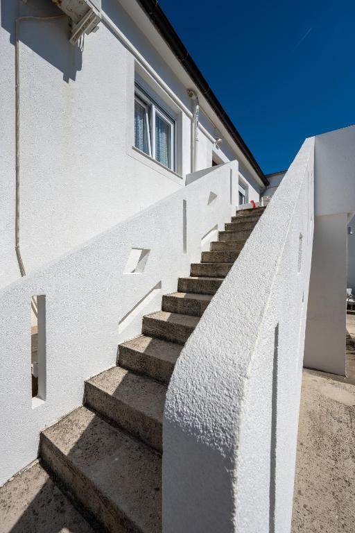 a set of stairs next to a white building at Apartments by the sea Stara Novalja, Pag - 6301 in Stara Novalja