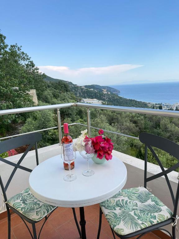 a table with two wine glasses and flowers on a balcony at Hotel Imperial in Dhërmi