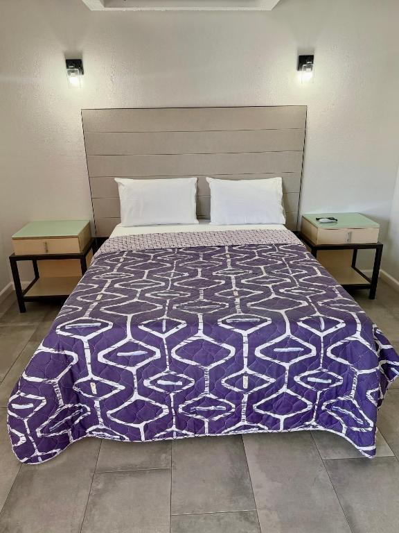 a bedroom with a purple bed with two tables at Rocky Inn Motel in Lynwood