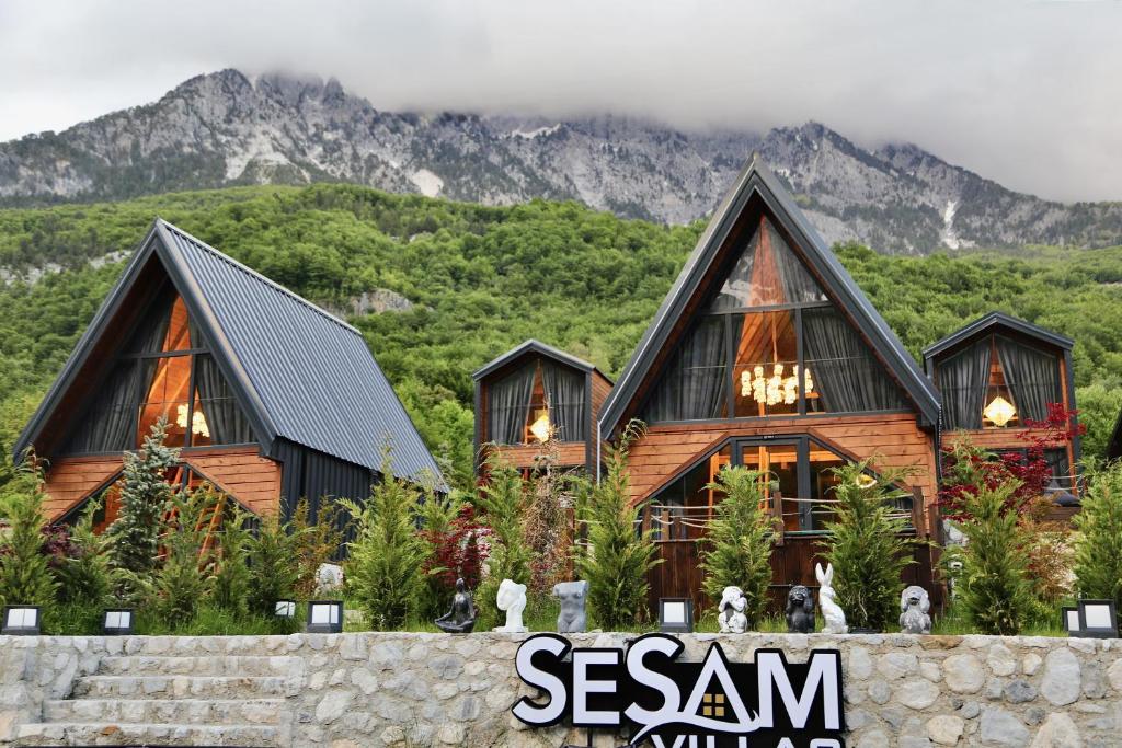 a large wooden house with mountains in the background at SeSam Villas in Theth