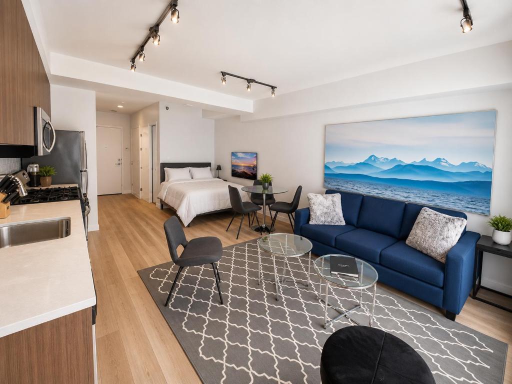 a living room with a blue couch and a bedroom at Perfect Brand New Studio Downtown Sidney in Sidney