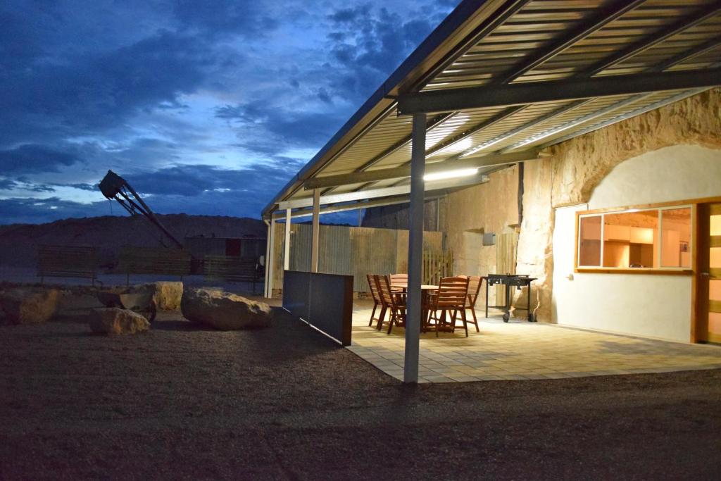 ein Gebäude mit einem Tisch und Stühlen auf einer Terrasse in der Unterkunft Dug Out B&B in Coober Pedy