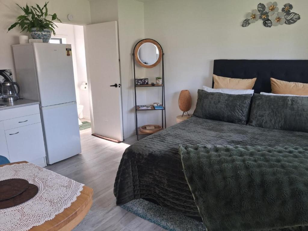 a bedroom with a bed and a mirror and a refrigerator at Private Studio providing a comfortable space in Paraparaumu