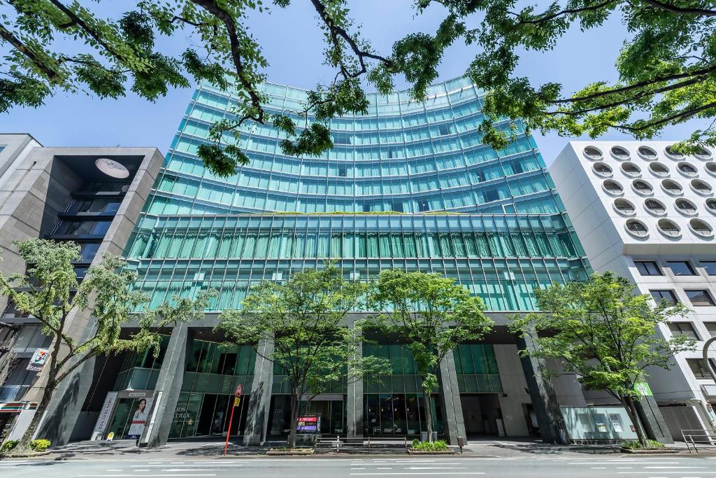 a tall glass building with trees in front of it at KOKO HOTEL Premier Hakata in Fukuoka