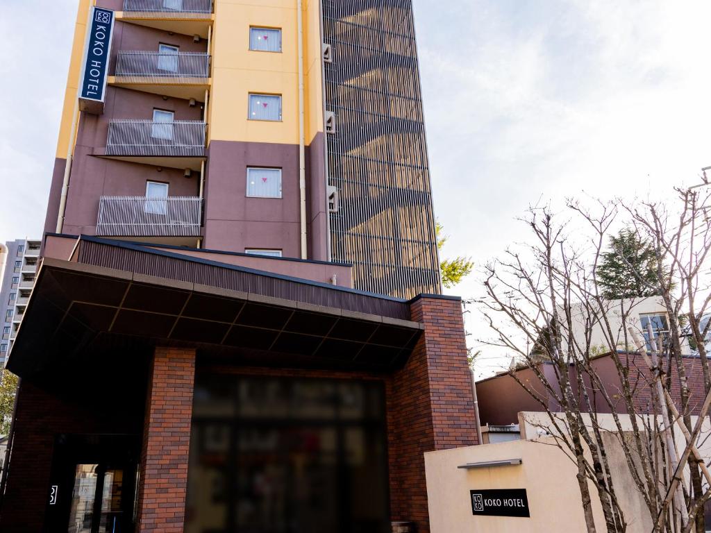 a tall building with a sign on top of it at KOKO HOTEL Akabane Station in Tokyo
