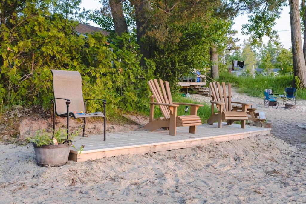 three chairs and a table on a wooden deck at Private Beach Access -Cottage 15 in Sauble Beach