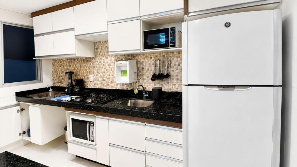 a white kitchen with a sink and a refrigerator at Seminate Apartamento in Franca