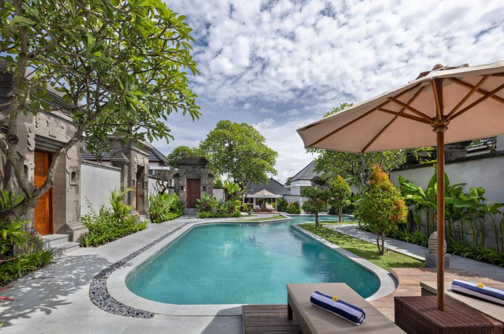 an image of a swimming pool with an umbrella at The Prime Seminyak by Kanaya Hospitality in Seminyak
