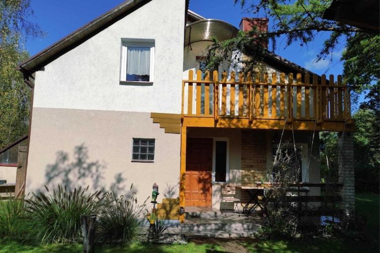 a house with a deck on top of it at Lakeside holiday villa, private garden in Wierzchowo