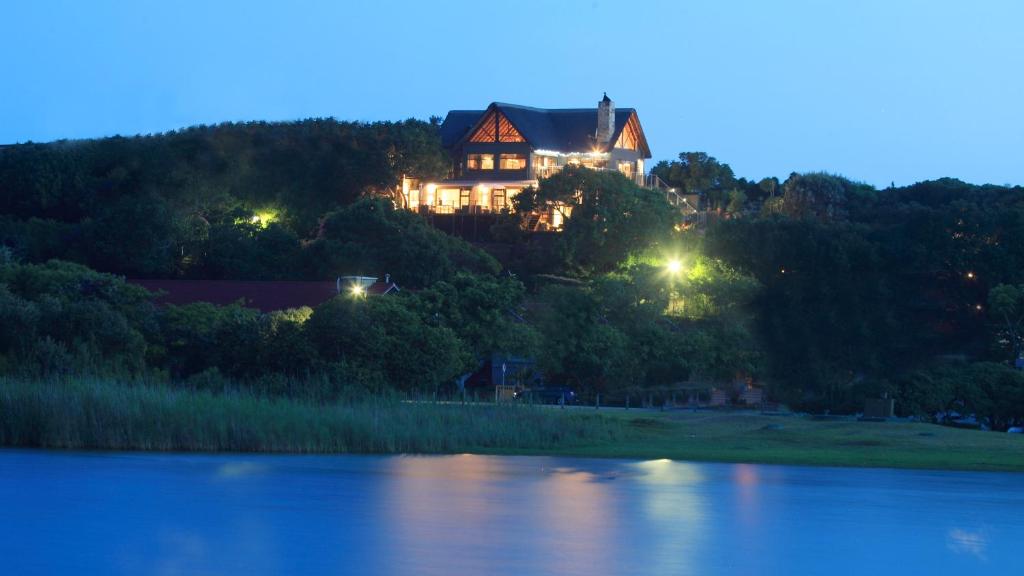 a house sitting on top of a hill next to a lake at Pearl Moon Boutique Suites in Wilderness