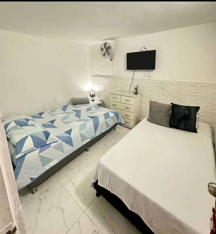 a bedroom with two beds and a flat screen tv at Hostal CAMPOAMOR in Medellín