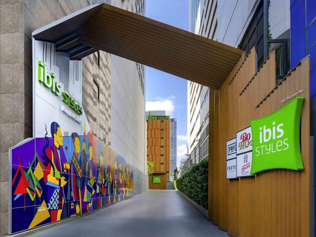 a hallway between two tall buildings with signs on them at ibis Styles Bangkok Silom in Bangkok