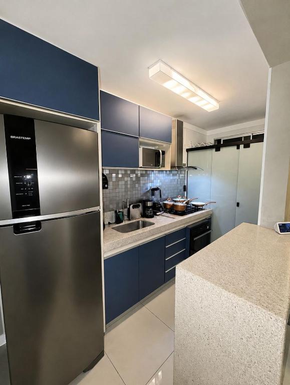 a kitchen with blue cabinets and a stainless steel refrigerator at apartamento Seminate 2 in Franca