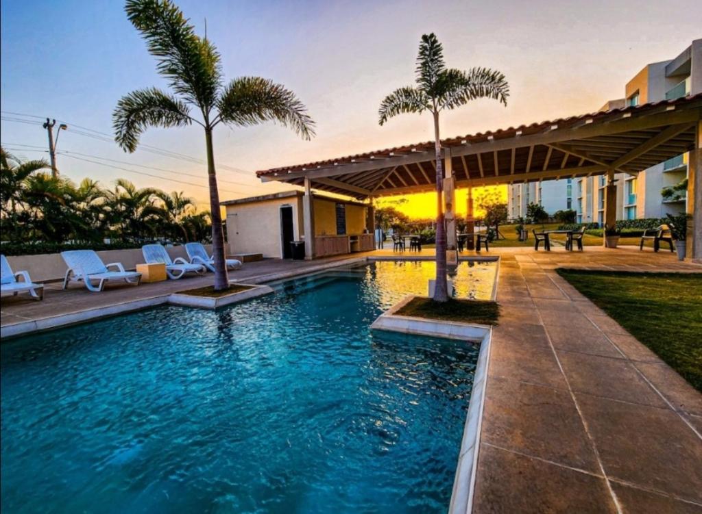 a pool with chairs and palm trees in a resort at Relax Terrace Condo Near Coronado Beaches in El Creo