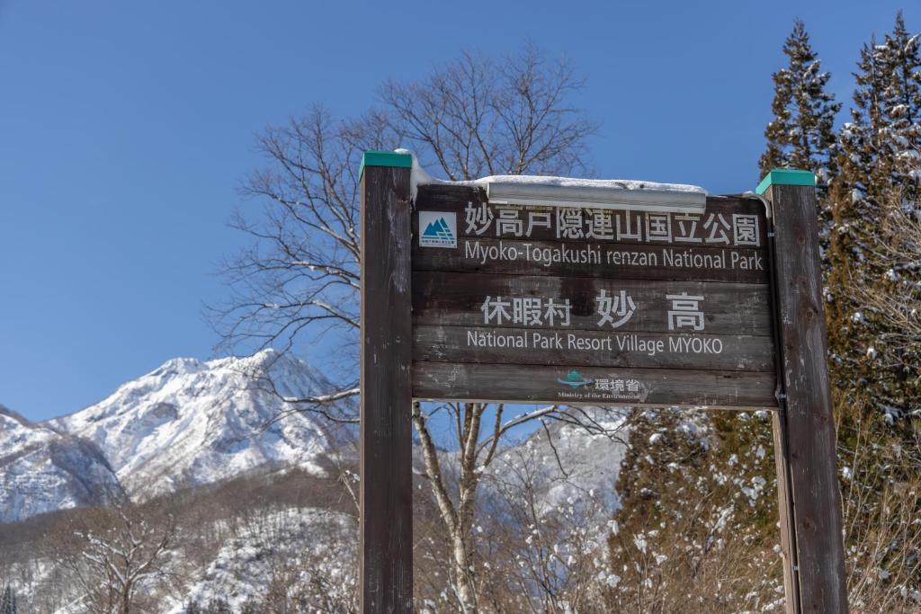 a sign in front of a snow covered mountain at Kyukamura Myoko in Myoko