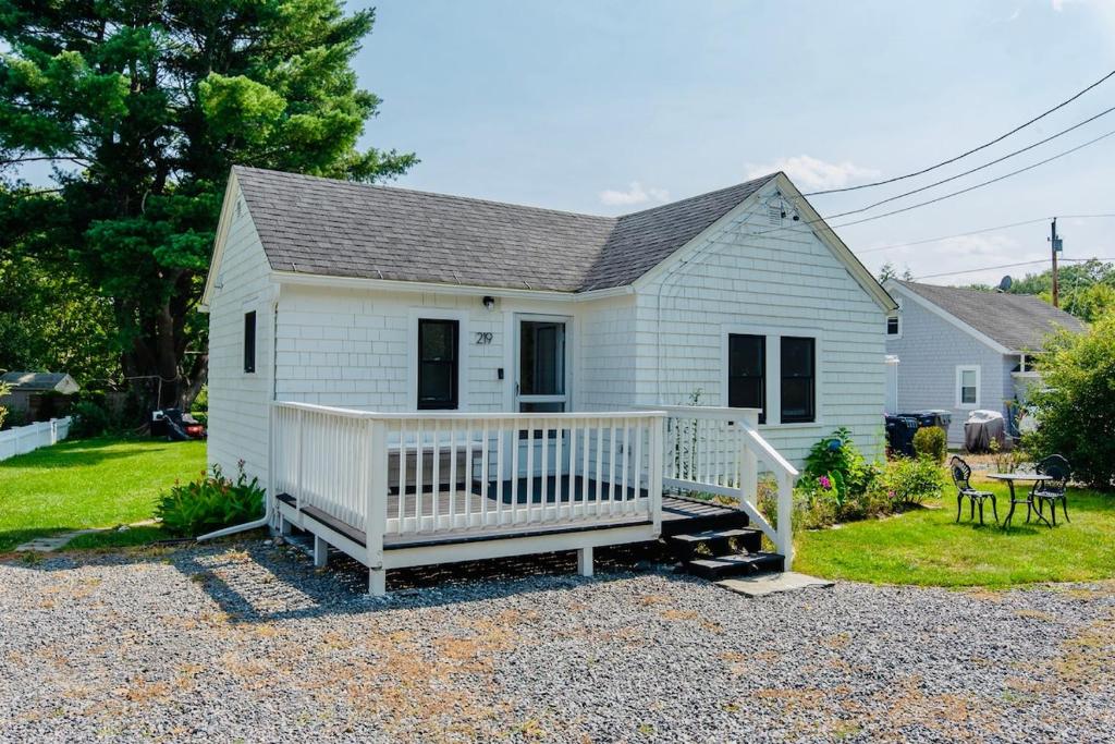 a small white house with a porch and a yard at Shorebreak Cottage in North Kingstown