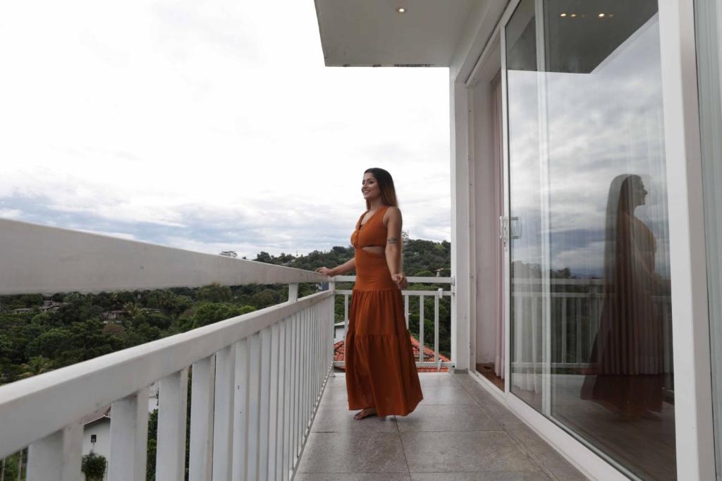 a woman in a orange dress standing on a balcony at Green Royal Villa in Kandy