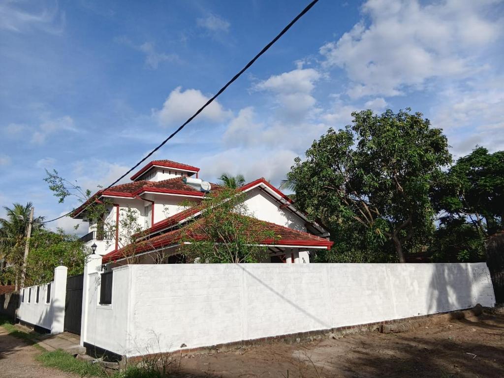 a house behind a white wall and a fence at Muthu Villa in Negombo