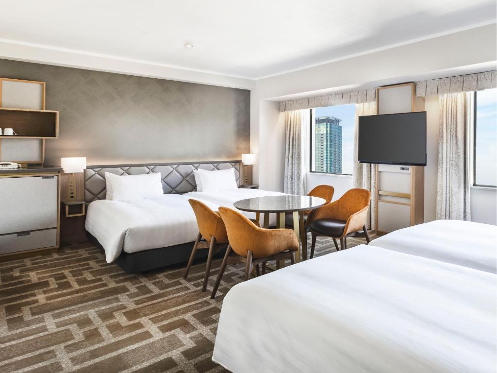 a hotel room with two beds and a table and chairs at Hotel Hanshin Osaka in Osaka