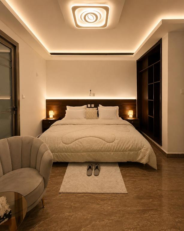 a bedroom with a large bed and a chair at Suite BMB in Abidjan