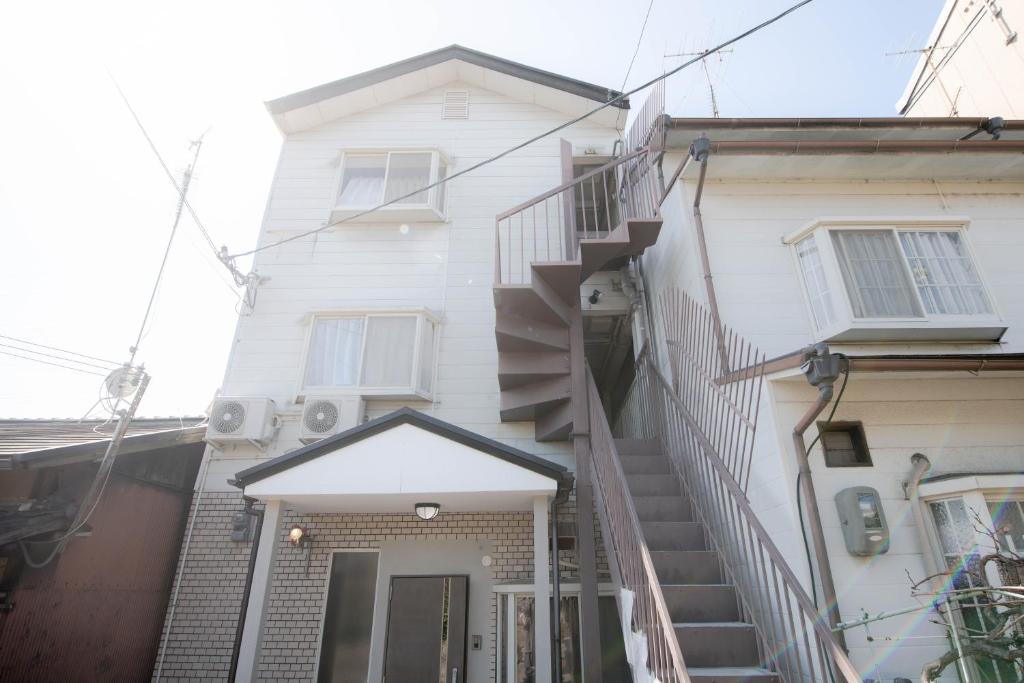 a white house with a staircase leading up to it at Ponpon Railway House in Kyoto