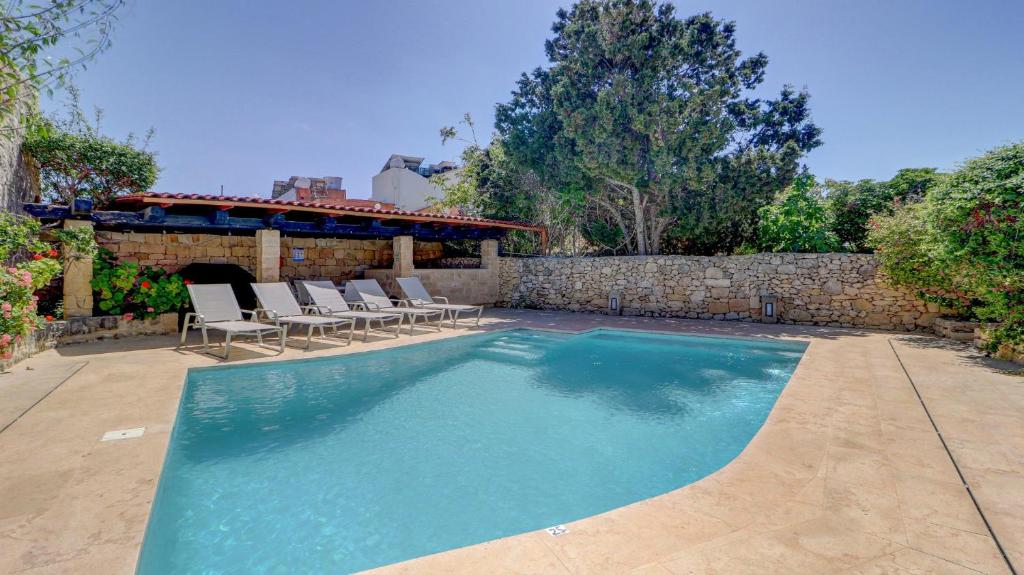 a swimming pool with chairs and a stone wall at Wonderful 4BR Farmhouse with Private Pool in Rabat