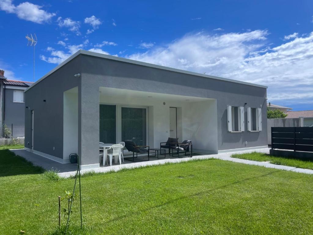 a small grey house with a green lawn at Casa Valeria in Abano Terme