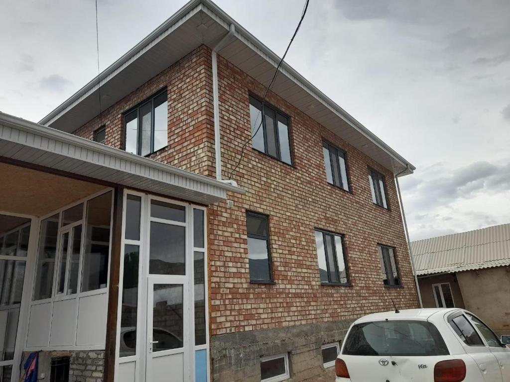 a brick building with a white car parked in front of it at Guest House Maral in Bokonbayevo