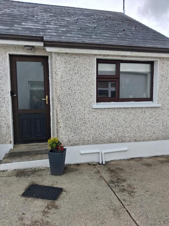 a house with a door and a potted plant at Teach Caitlin in Ballina