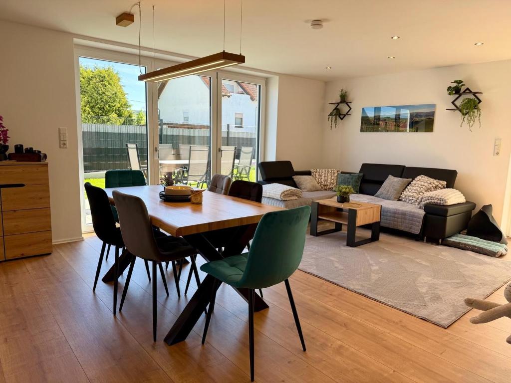 a dining room and living room with a table and chairs at Ferienwohnung zum Buchfeld in Windesheim