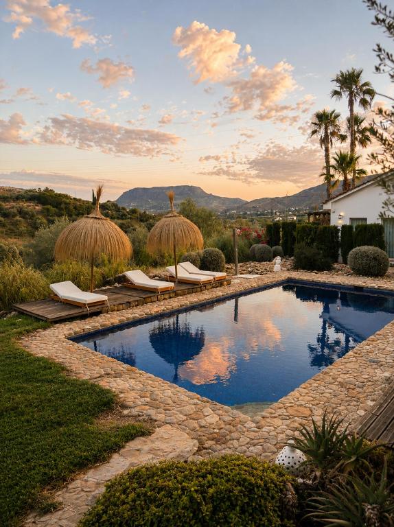 a swimming pool with chairs and umbrellas in a yard at Finca Dariana Padel & Pool in Alora