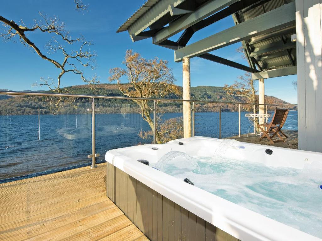 a hot tub on a deck with a view of the water at Dipper Boathouse in Acharn