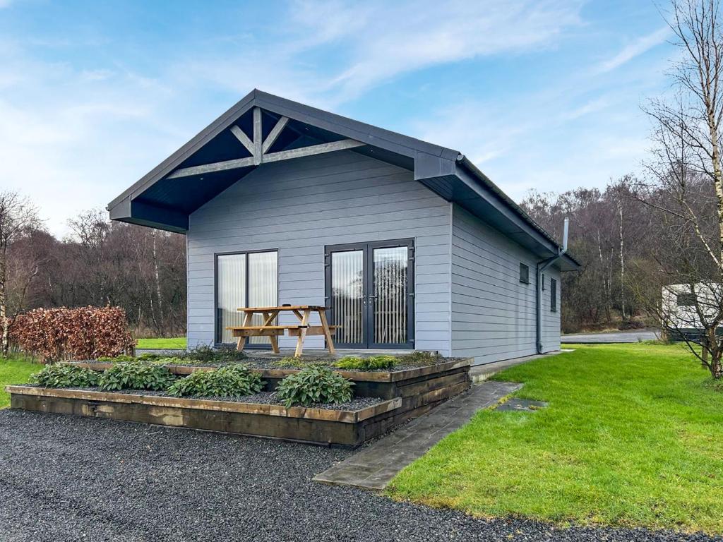a small house with a picnic table in a yard at Bellstane Chalet - Ukc9440 in Glasgow